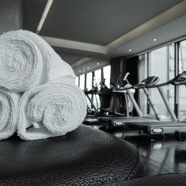Toallas blancas de gimnasio enrolladas frente a una fila de caminadoras