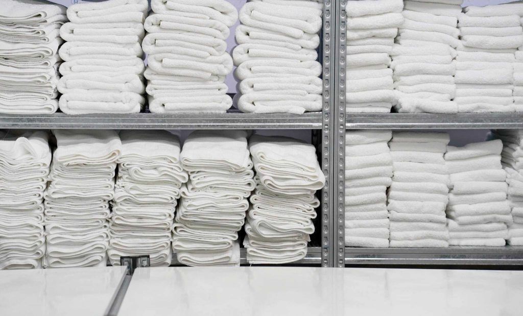 Pilas de toallas blancas recién lavadas en repisas, listas para los huéspedes del hotel