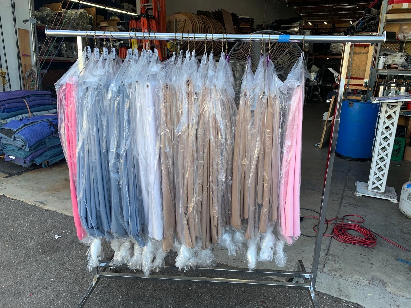 Freshly pressed linens in garment bags on a rolling rack, ready for delivery