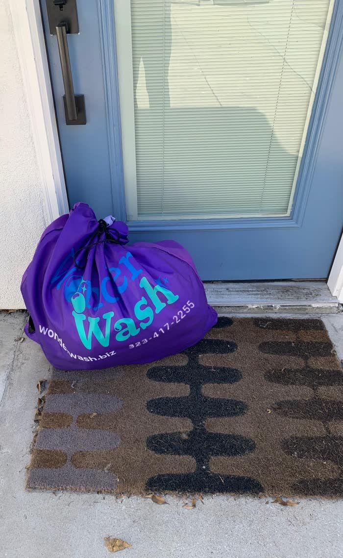 A WonderWash laundry bag on a doormat, ready for pickup